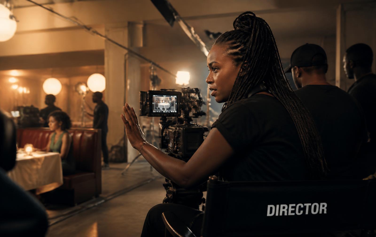 Black woman director reviewing a monitor on a warm-lit film set